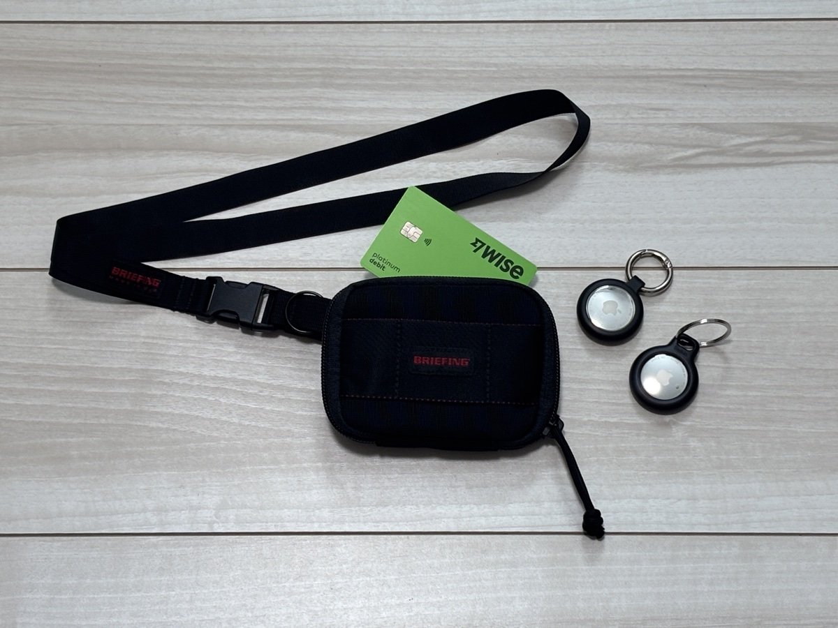 防犯3軸の実物一式。AirTag2個、BRIEFING NECK HOLDERとROUND ZIP WALLET MW、Wiseデビットカード